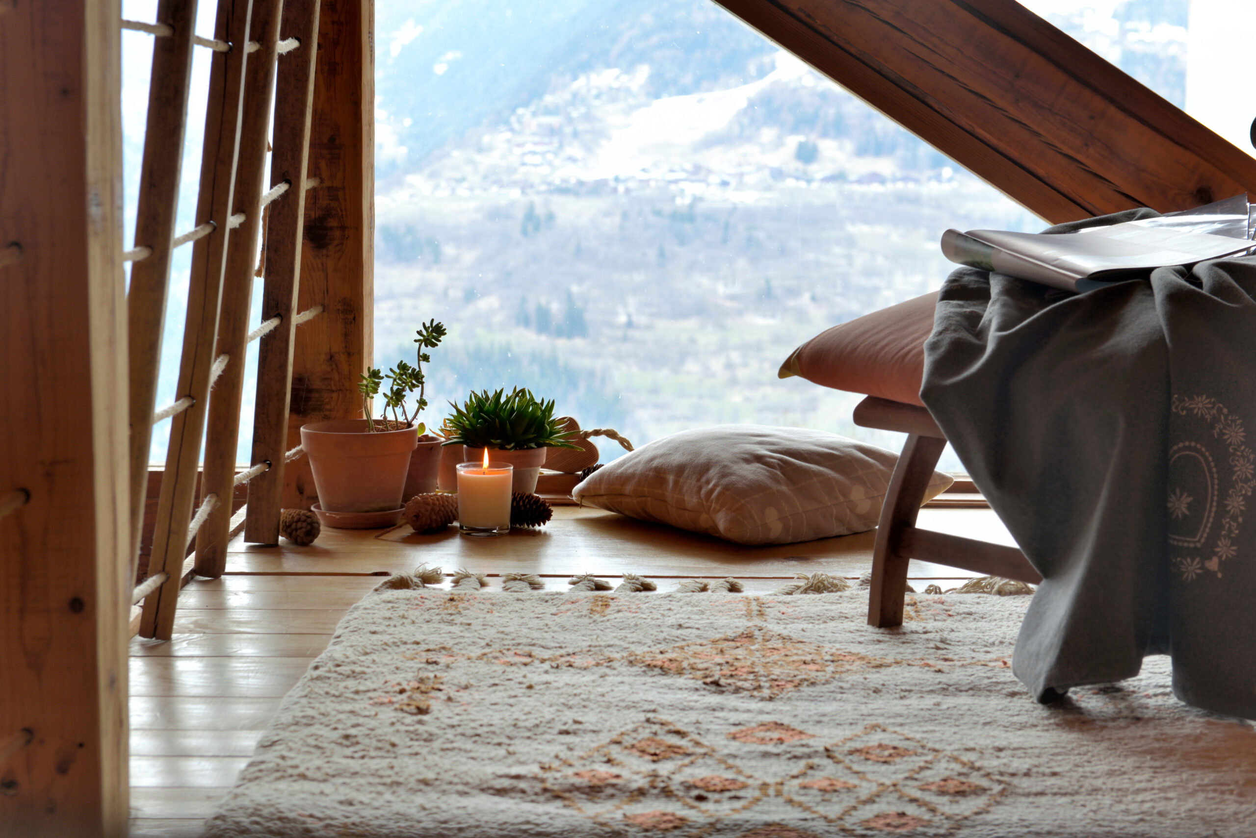break room with chair, plants and candle in front of paned glass in a cottage of mountain